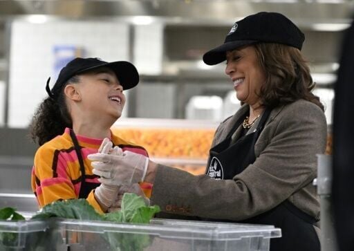 US Vice President Kamala Harris speaks with her great-niece Leela Ajagu as they help prepare Thanksgiving dinner at DC Central Kitchen in Washington, DC